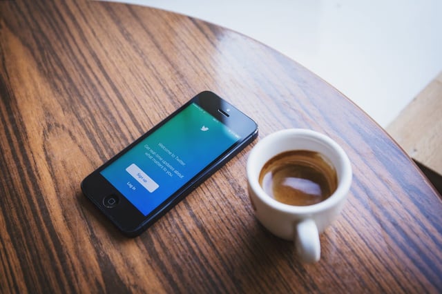 Twitter login page on phone with cup of coffee on desk