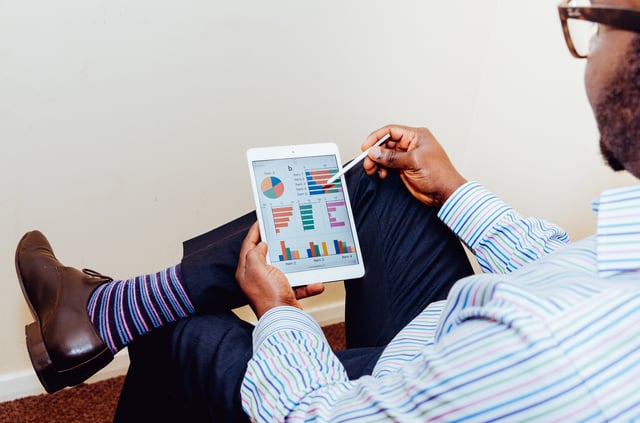 Man sat on chair looking at graphs on tablet